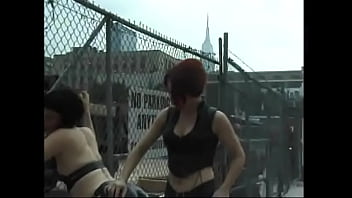 Red-haired bitch in a leather suit hits the nipples and ass of a lustful brunette in the parking lot
