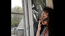 smoking woman with makeup by the window