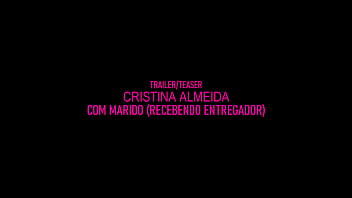 Marido da Cristina Almeida recebendo entregador, enquanto ela fica de perninhas aberta com a buceta exposta no sofá mexendo no celular.